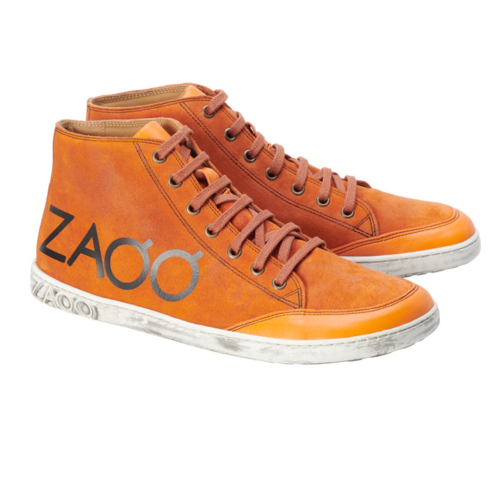 Die SQYLA Orange Sneaker von ZAQQ, perfekt für Damen, bestechen durch ihr leuchtend oranges Design mit braunen Schnürsenkeln und einer klassischen weißen Sohle. Die Seite ist mit dem Markennamen ZAQQ in fetten schwarzen Buchstaben verziert. Mit ihrem leicht abgenutzten Look verkörpern diese Sneaker eine Vintage-Ästhetik, die an Barfußschuh-Styles erinnert.