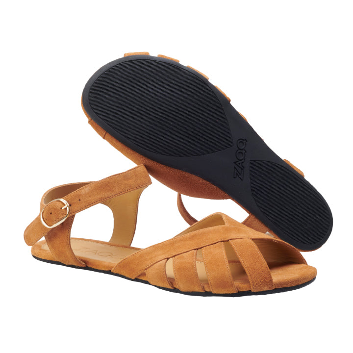 Ein Paar schicke QORSE Brown Damensandalen von ZAQQ verkörpert den perfekten Sommerlook. Eine Sandale steht aufrecht und zeigt einen überkreuzten Riemen mit Schnallendetail am Knöchel, während die andere ihre strukturierte schwarze Sohle offenbart, die bei jedem Schritt sowohl Stil als auch Komfort bietet.