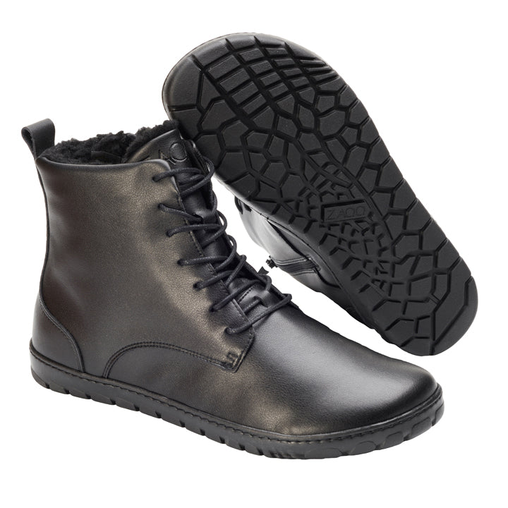 Die QUINTIC Winter Vegan Black Stiefeletten von ZAQQ präsentieren sich in einem eleganten, schwarzen Lederdesign mit schwarzen Schnürsenkeln und strukturierten Gummisohlen. Ein Stiefel steht aufrecht und betont sein Seitenprofil, während der andere geneigt ist und die gemusterte Sohle freigibt. Das oben sichtbare Plüschfutter sorgt für zusätzliche Wärme.