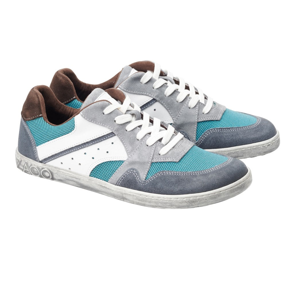 Wir präsentieren den BREAQ Turquoise von ZAQQ, ein Paar stylische Sneaker mit blaugrünen, weißen und grauen Einsätzen, ergänzt durch weiße Schnürsenkel und braune Akzente. Diese Schuhe wurden mit Blick auf außergewöhnlichen Komfort entworfen und bieten bei jedem Schritt sowohl Flair als auch Funktionalität.