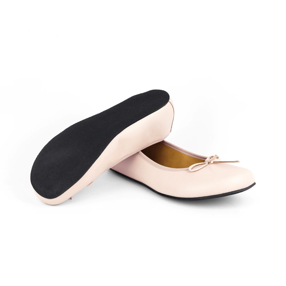 Ein Paar LOOQ Nude Ballerinas von ZAQQ in Hellrosa, einer liegt auf der Seite und hat eine schwarze Sohle, der andere steht aufrecht und hat eine kleine Schleife. Sie strahlen Eleganz aus und sind bekannt für ihre bequeme Passform, vor einem schlichten weißen Hintergrund.