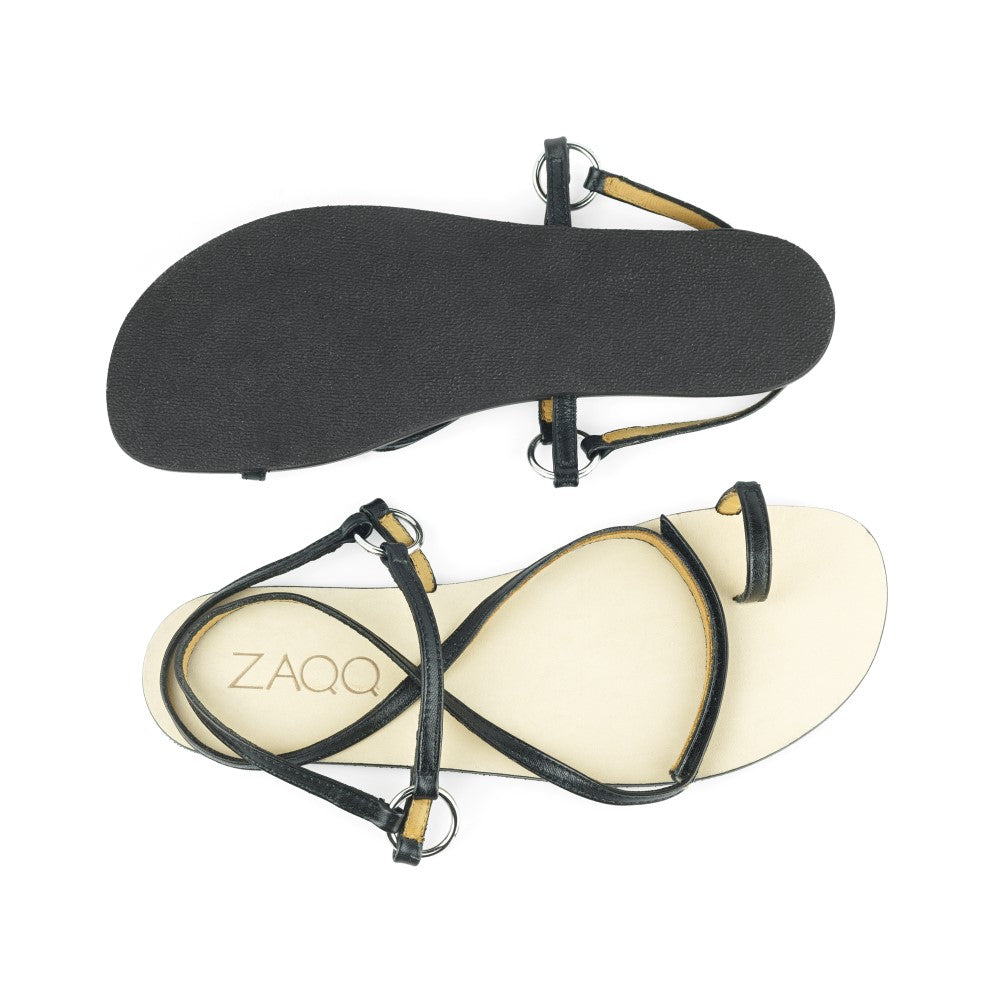 Ein Paar minimalistische schwarze MINIQ-Sandalen, ideal für einen schicken Sommerlook, bei dem eine Sandale von oben und die andere von unten zu sehen ist. Diese ZAQQ-Sandalen zeichnen sich durch ein schlichtes Design mit dünnen Riemen und einem hellen Fußbett aus, das mit dem Markennamen MINIQ verziert ist.