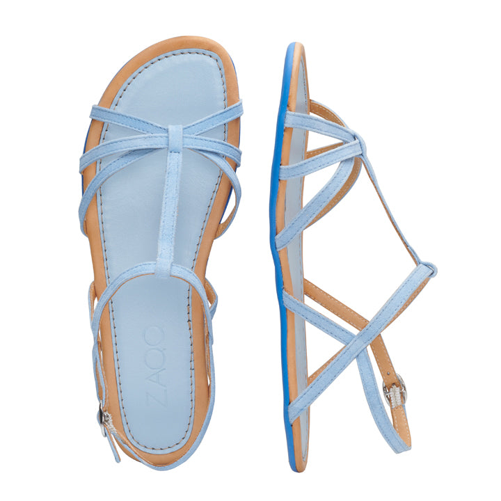 Wir präsentieren die QADA Blue von ZAQQ: Damensandalen mit dünnen Riemen in einem hellblauen Farbton, der von oben und von der Seite präsentiert wird. Diese Sandalen haben ein hellbraunes Fußbett und werden mit einem Schnallenverschluss am Knöchelriemen gesichert. Sie sind mit einer hochflexiblen Barfußsohle ausgestattet, um ultimativen Tragekomfort zu bieten.