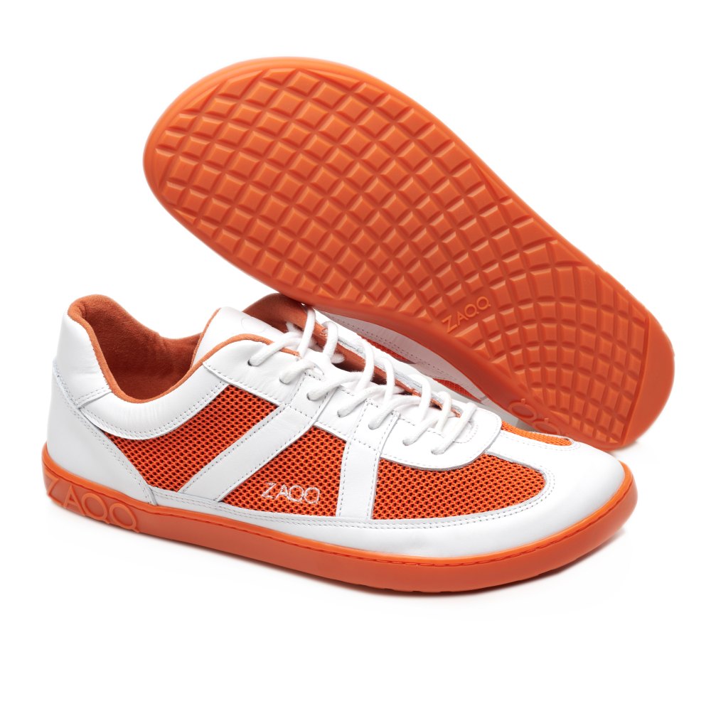 Ein Paar Sneaker in Weiß und Orange von OAQLEY mit ultramodernen Mesh-Details und Gummisohlen. Ein Schuh steht aufrecht, während der andere auf der Seite liegt, um die Textur der Sohle hervorzuheben. Das ZAQQ-Markenlogo fällt auf diesen stylischen Barfuß-Sneakern auf.