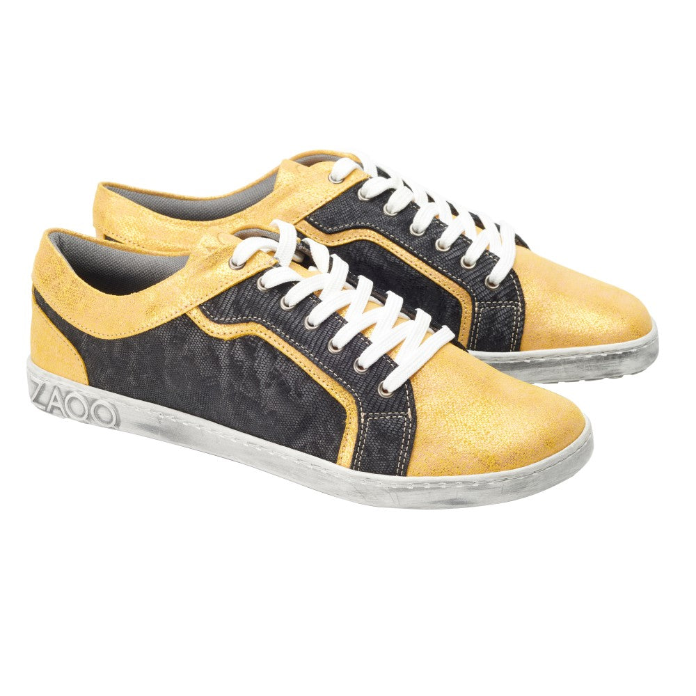 Wir präsentieren die QODY Gold Low-Top-Sneaker von ZAQQ, eine perfekte Mischung aus Stil und Komfort. Diese von Barfußschuhen inspirierten Schuhe präsentieren sich in schickem goldgelbem und schwarzem Farbblockdesign, gepaart mit weißen Schnürsenkeln und einer eleganten weißen Sohle mit ZAQQ-Prägung an der Seite, alles vor einem makellosen Hintergrund.