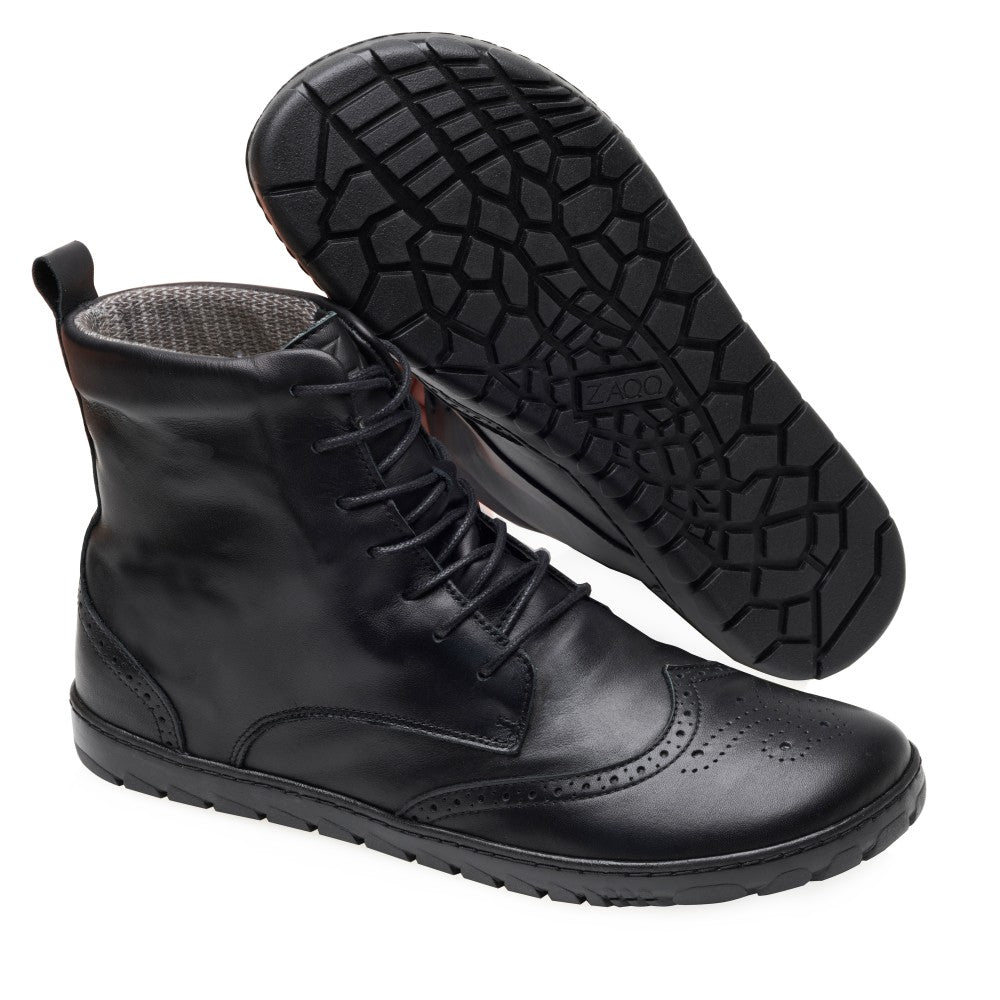 Wir präsentieren den QUINTIC Brogue Black Waterproof von ZAQQ: ein Paar exquisite schwarze Lederstiefel aus weichem Nappaleder mit Schnürung und elegantem Brogue-Detail an der Spitze. Ein Stiefel steht aufrecht, während der andere angewinkelt ist, um seine aufwendig strukturierte Sohle zur Geltung zu bringen.