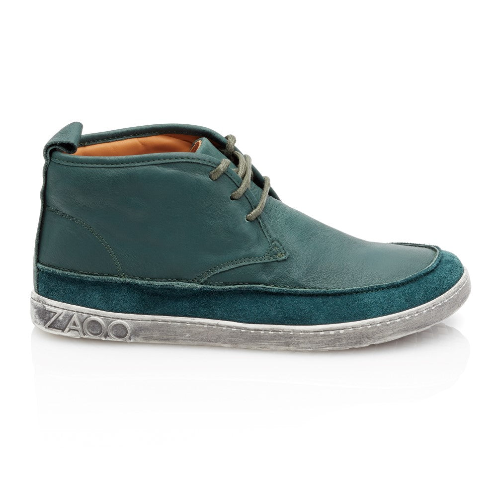 Wir präsentieren den High-Top-Sneaker QUITMAN Green von ZAQQ, gefertigt aus luxuriösem Velours und Glattleder in einem auffälligen Grünton. Dieser Schuh verfügt über eine flexible weiße Gummisohle, dunkelgrüne Schnürsenkel und zeigt stolz den Markennamen, der auf der Seite eingeprägt ist. Er wird durch eine Wildlederstruktur an der Unterseite zusätzlich aufgewertet.