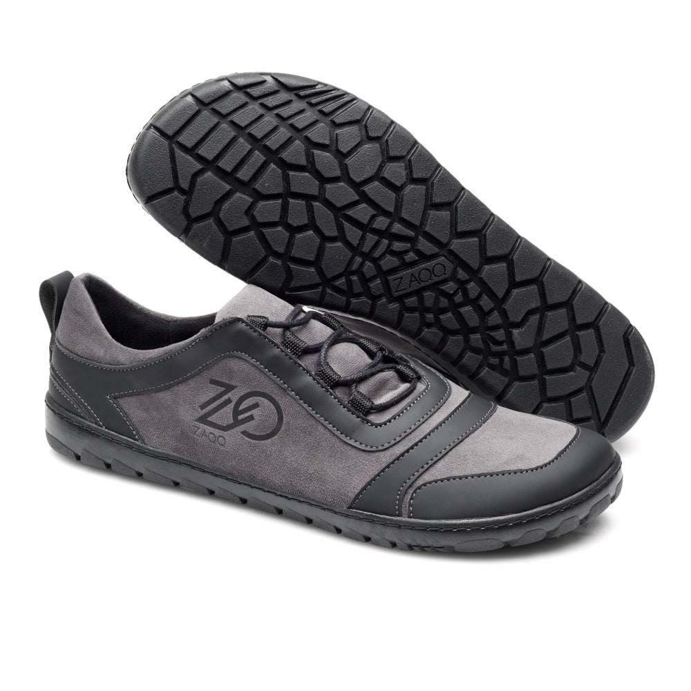 Die SQILL Ash Sneaker von ZAQQ in Grau und Schwarz zeigen ein markantes Muster auf der Sohle und sind ideal für Outdoor-Abenteuer. Sie kommen mit einem geradlinigen Schnürdesign und einem stylischen Logo an der Seite.