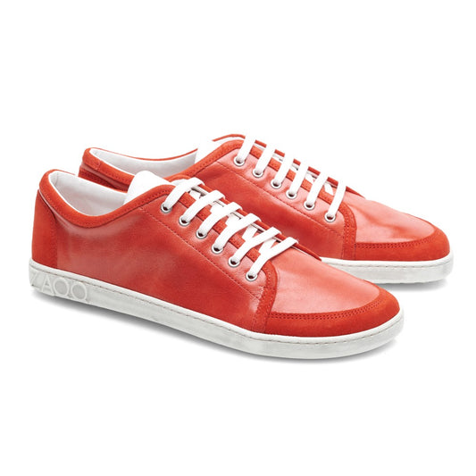 Die TIQQ Red-Sneaker von ZAQQ zeichnen sich durch ein glänzendes rotes Lederdesign mit weißen Schnürsenkeln und Sohlen aus, das sich vor einem schlichten weißen Hintergrund abhebt. Diese Sneaker bieten eine schlichte und klassische Ästhetik und verleihen jedem lässigen Outfit Eleganz.