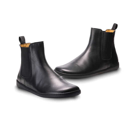 Ein Paar elegante Chelsea-Stiefel aus schwarzem Leder von ZAQQ EQUITY mit eleganten Seitenteilen mit Gummiband und praktischen Aufreißlaschen an der Rückseite, präsentiert vor einem strahlend weißen Hintergrund.