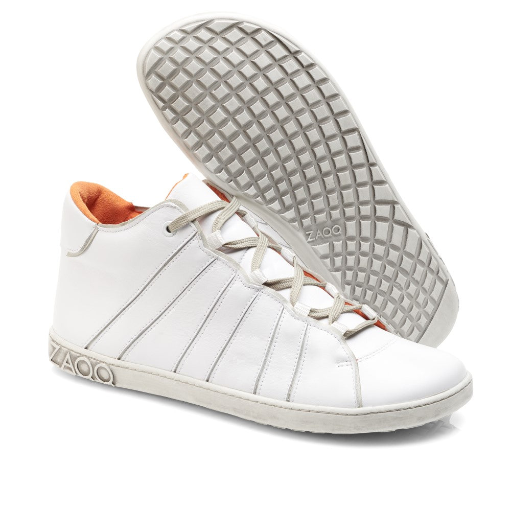 Der QQQ Mid White von ZAQQ ist ein Paar weißer High-Top-Sneaker aus hochwertigem Nappaleder mit orangefarbenem Innenfutter und grauer Sohle. Ein Schuh steht aufrecht, während der andere sich neigt und seine Barfußschuhsohle mit Waffelmuster zeigt. Der Markenname ZAQQ ist elegant auf der Seite und der Sohle angebracht und unterstreicht ihr stilvolles Design.